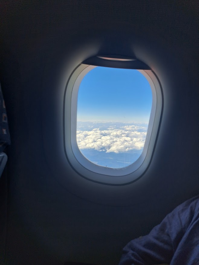 Plane window looking at clouds